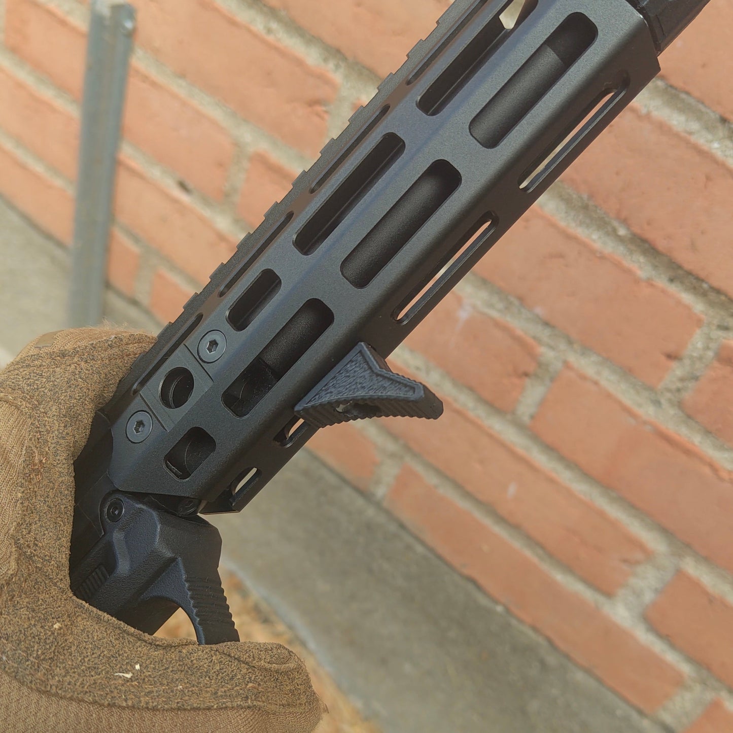 Close-up of a black rifle stock on a brick surface
